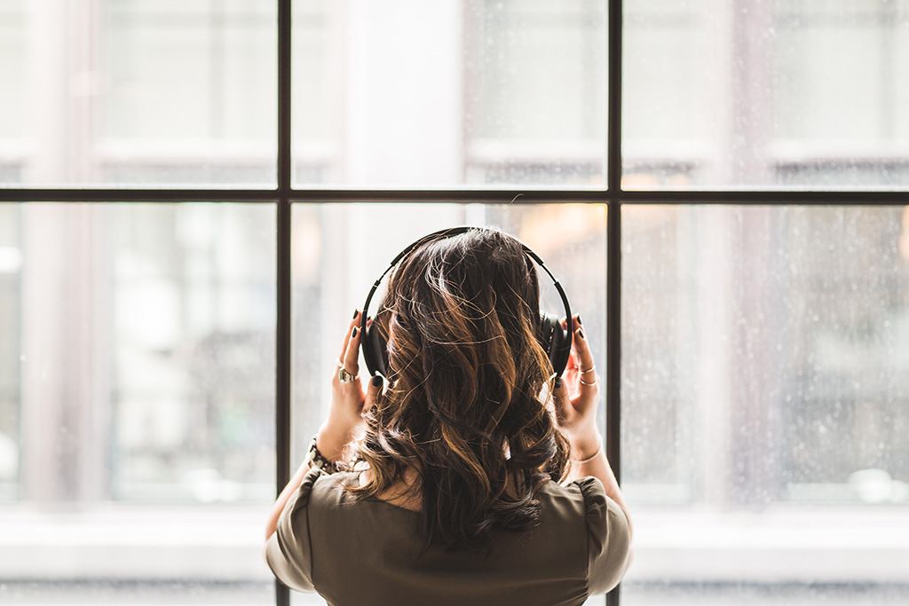 girl looking out window with headphones on