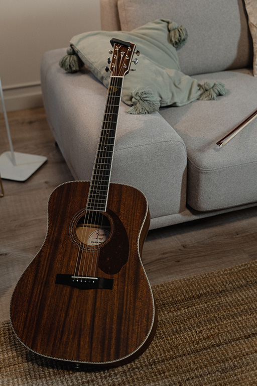 Guitar laying beside a couch
