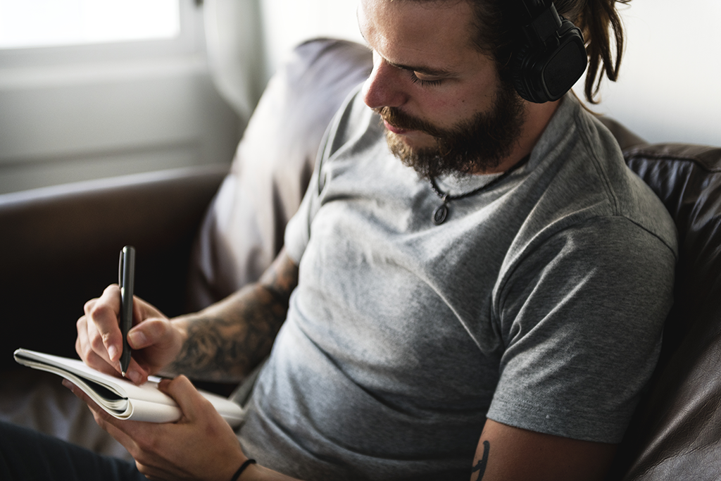 Man writing with headphones on