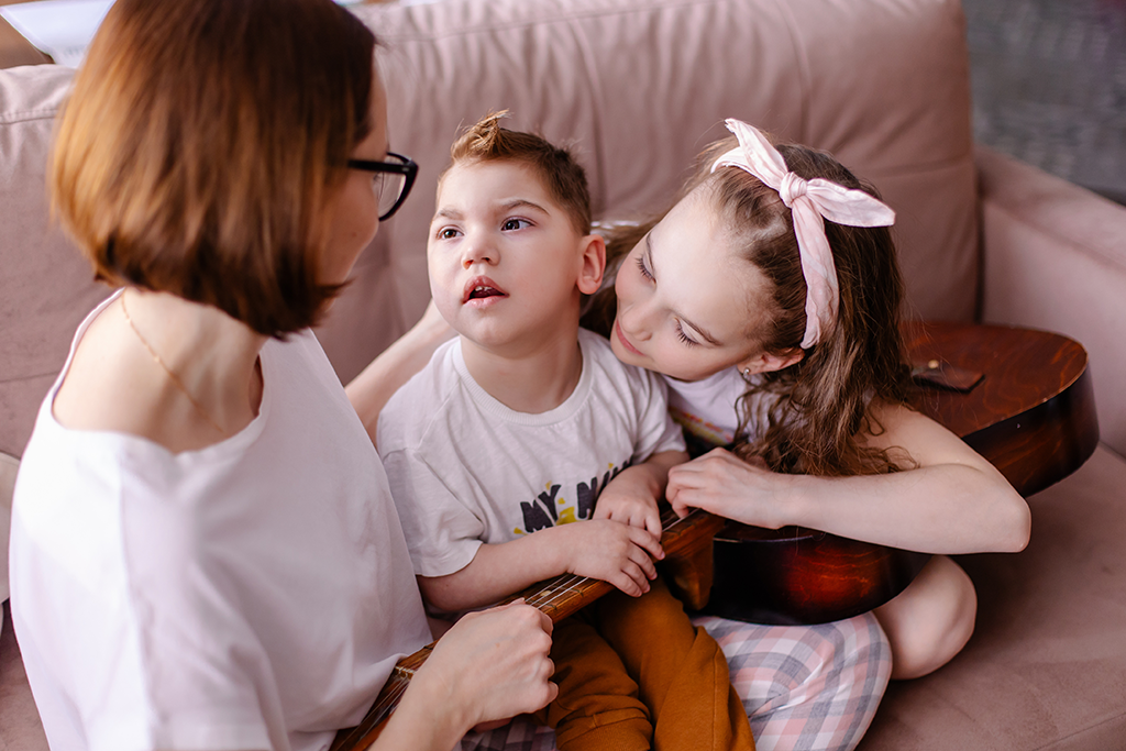 mom and sister comforting child with autism holding a guitar
