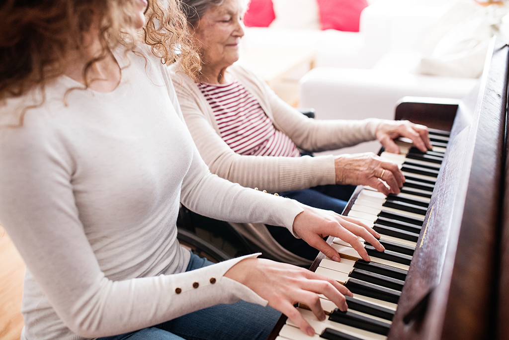 women playing piano with elderly woman