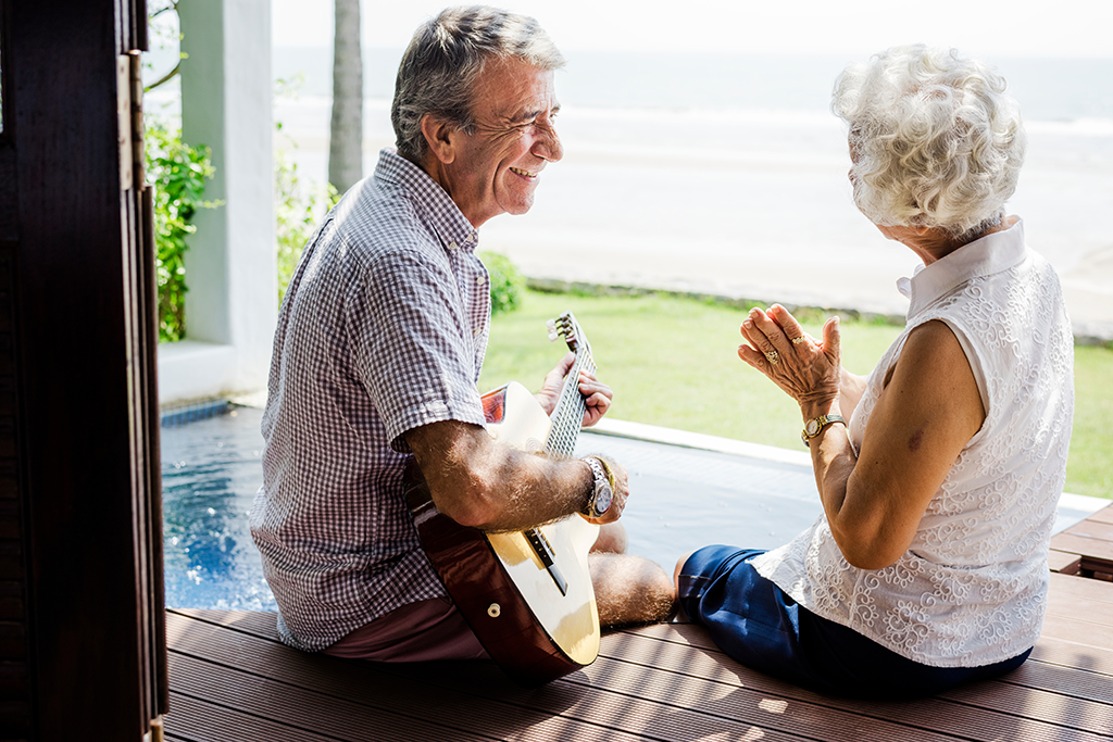 elderly man playing guitar for elderly woman